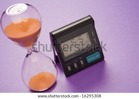 An ancient hour-glass-style egg-timer and a modern digital clock.