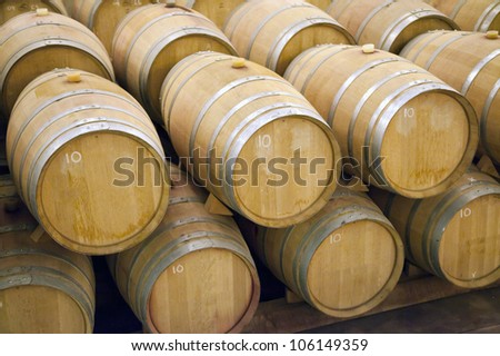 A stack of wooden barrels in a winery, aging wine.
