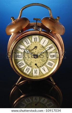 Old fashioned alarm clock on a blue background.