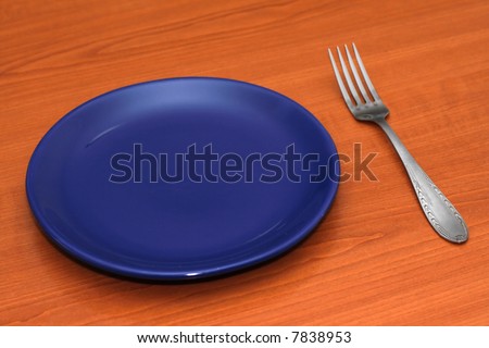 Blue empty plate and a fork on a table