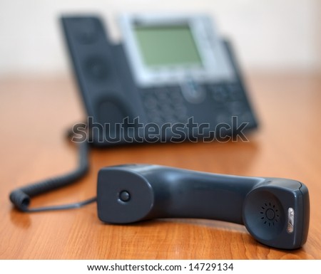 Phone receiver lying on a table, shallow depth of field with focus on the speaker of the receiver