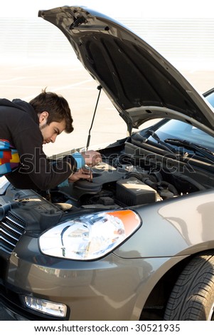 Car driver examining the car's engine on a parking