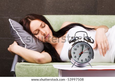 Vintage alarm clock, with beautiful young woman sleeping in the background
