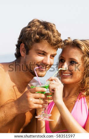 Young cheerful couple on the seaside with cocktails