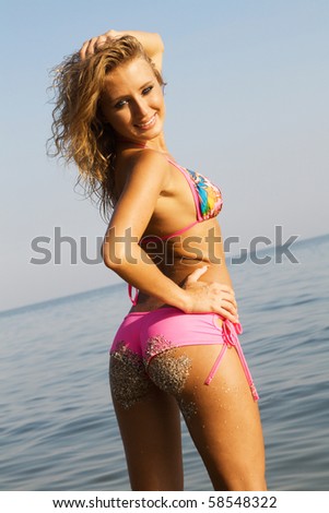 Sexy young woman in pink bikini standing in the sea