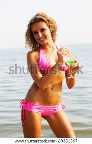 Beautiful model in pink bikini with cocktail at the seaside