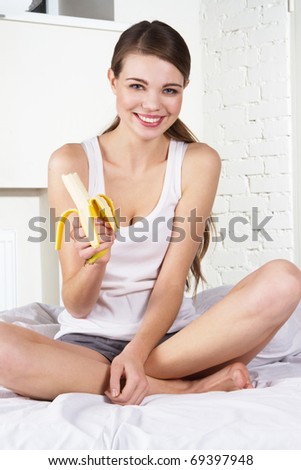 Beautiful woman eating a banana, at home in the morning