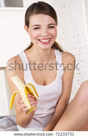 Beautiful woman eating banana, at home in the morning