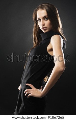 Beautiful fashion model in strict black dress, neutral background