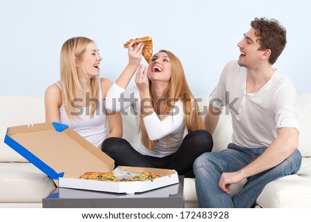 Group of young people eating pizza at home