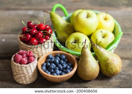 Fresh juicy apples, pears and berries on a wooden table