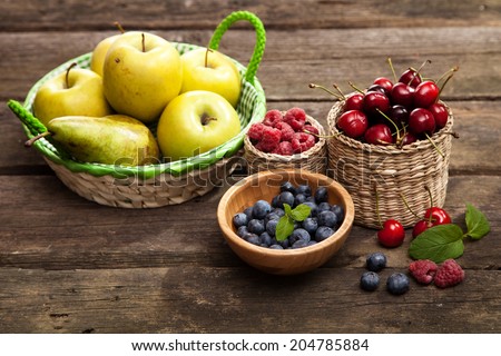 Fresh juicy apples, pears and berries on a wooden table