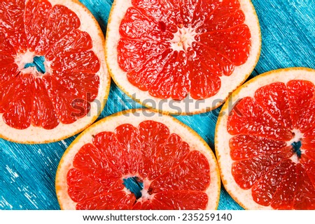 Red grapefruit slices on blue wooden background