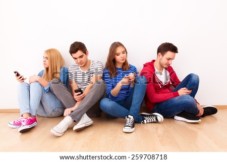 Group of four young people busy with their smartphones