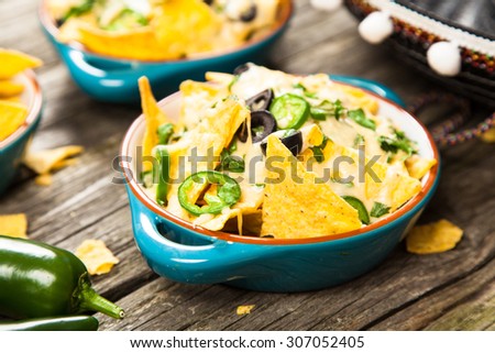 Nachos with melted cheese and salsa, guacamole and cheese dips
