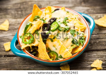Nachos with melted cheese and salsa, guacamole and cheese dips