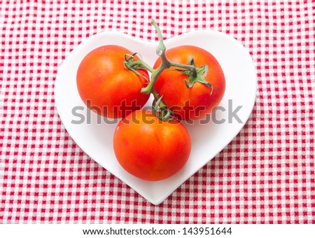 three tomatos  on heart white plate