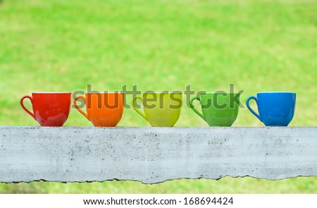 Colorful coffee cups on green field  background
