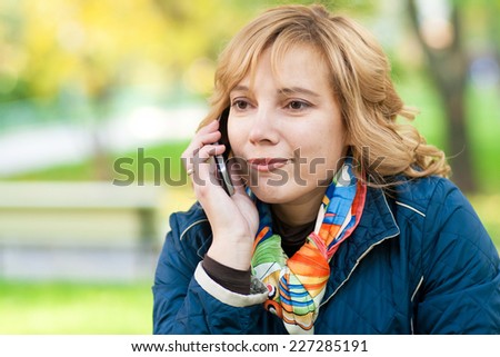 Portrait of a young blond woman talking on mobile phone on the street
