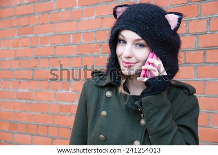Young woman in a funny knitted hat talking on mobile phone on the street