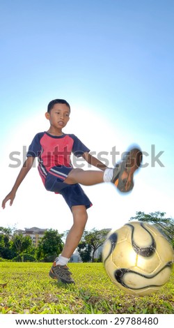 A boy is kicking a ball during evening