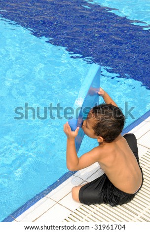 A boy kisses the floating board at the side of swimming pool