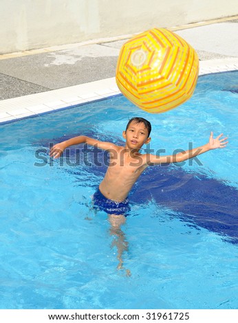 Kid plays with light yellow ball inside swimming pool
