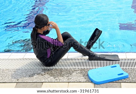 A girl prepares to swim with a floating board at the side of swimming pool