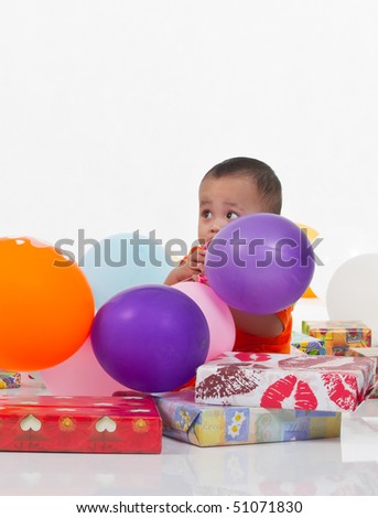 Little boy plays together with colorful of present boxes and balloons