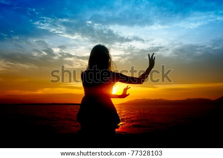 Silhouette of young sensuality beautiful woman performs traditional dance move during sunset