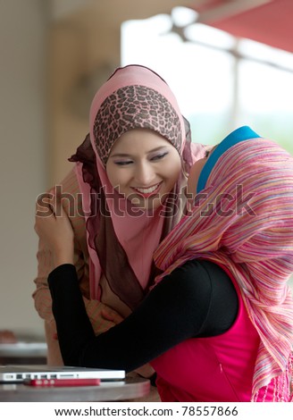 Pretty young Asian Muslim woman meeting friend at coffee shop
