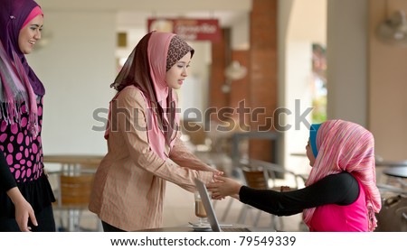 Pretty Asian Muslim college girls greeting friends at coffee shop