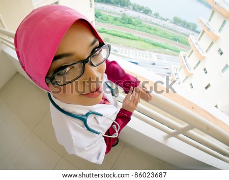 Close-up portrait of female Muslim doctor or nurse with stethoscope. High angle view with fish-eye effect.