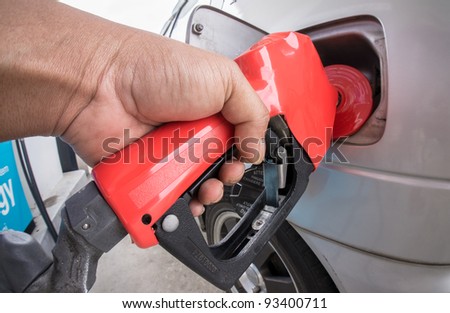 Close-up of a man\'s hand using a petrol pump to fill-up his car with fuel