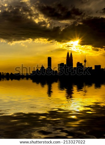 Kuala Lumpur City Center in silhouette during sunset surrounding with water flood. digital compositing with colour tone, water reflection and ripple effects.