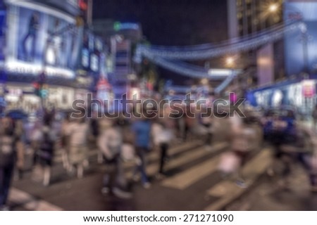 Busy people on street at night in defocused blur concept with vintage color style.