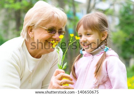 little girl giving her great grandmother yellow flowers