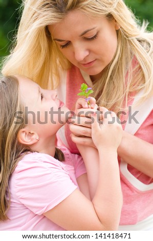 little girl giving her mother flowers outdoors
