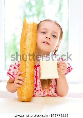 cute little girl with a glass of milk and long loaf