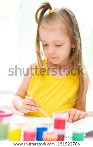 cute little girl painting with paintbrush and colorful paints