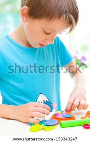 cute little boy is playing with colorful play dough