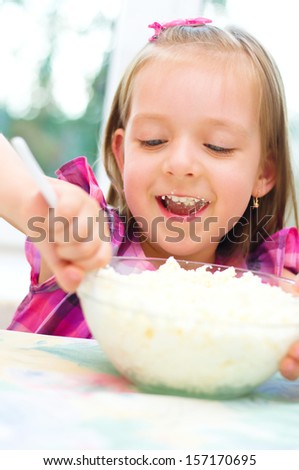 Healthy food. Cute little girl is eating cottage cheese, curd