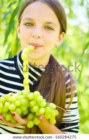 Cute teenage girl holding grapes and drinking grapes juice outdoors