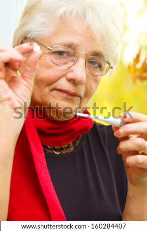 senior woman holding a pill in her hand, preparing to eat that - part of a series.