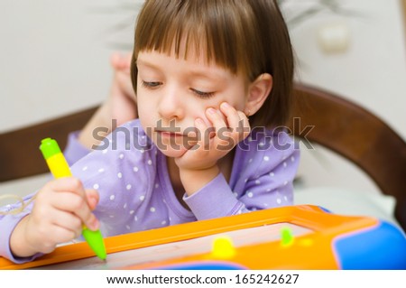 Little girl writing at magnetic drawing board