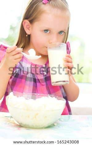 healthy food, child is eating cottage cheese, curd and drinking milk