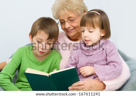 Grandmother reading a book for grandchildren at home