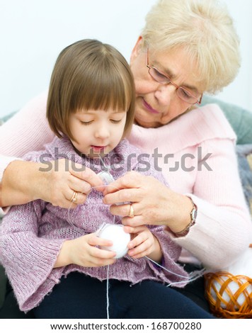 cute little girl and her granddaughter knitting together