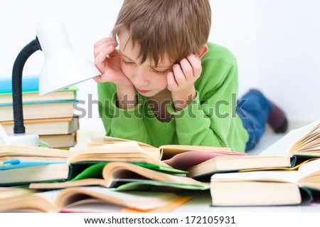 schoolboy reading book lying down on floor