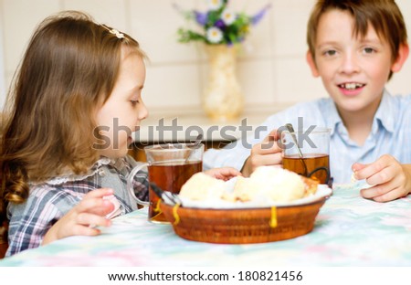 little girl with her brother sitting at the table drinking tea